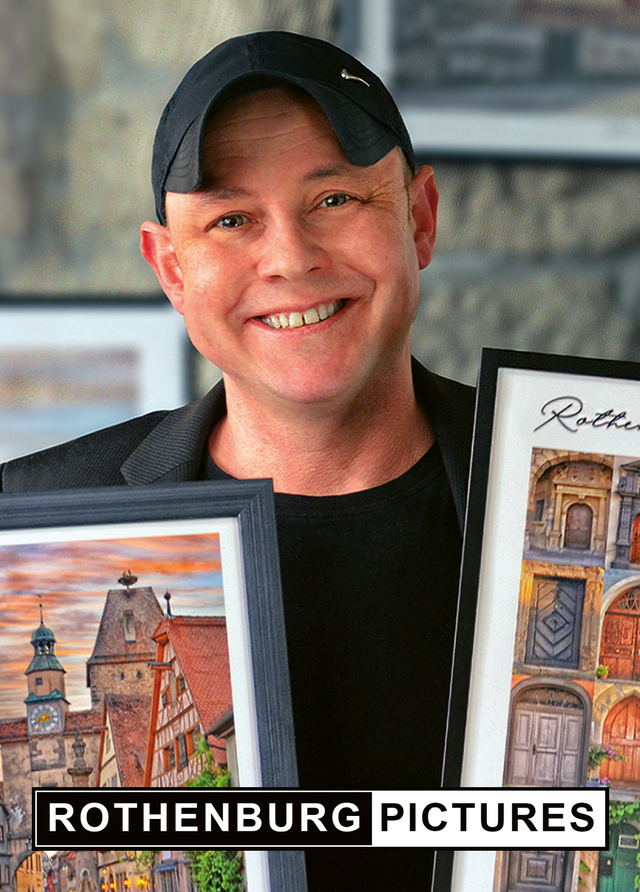 Alexander Möller, Fotograf und Inhaber von ROTHENBURG PICTURES in Rothenburg ob der Tauber, mit zwei gerahmten Fotografien seiner Heimatstadt.
